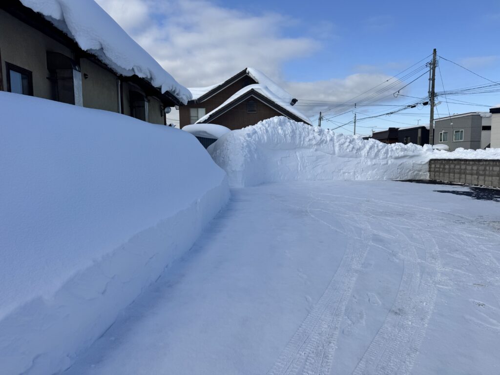 北海道銭函の冬の様子。除雪されて高く積み上がった雪の壁と、雪道の轍