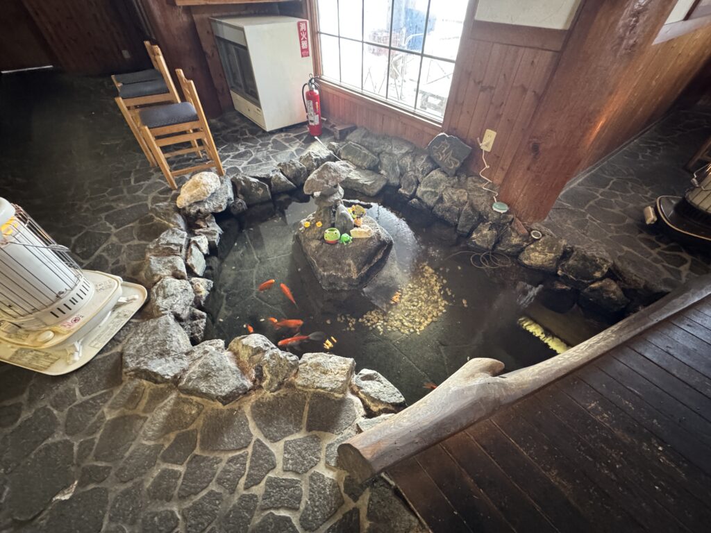 銭函の食事処「貴勝」の店内にある、金魚が泳ぐ岩組みの池と暖かいストーブ